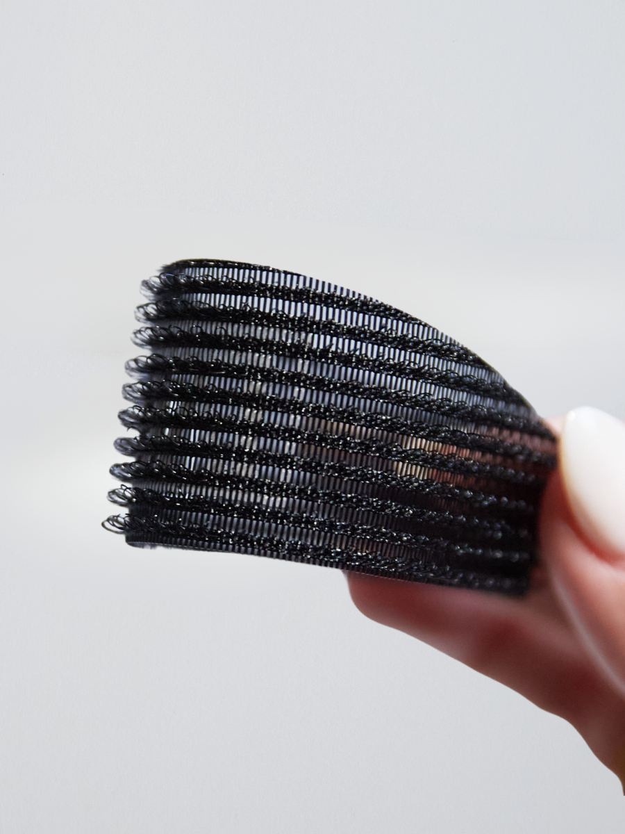  A detailed close-up of KOVI curved hair grippers showcasing the textured, non-slip surface. The lightweight yet strong grip holds hair in place, preventing flyaways during hair extension application.