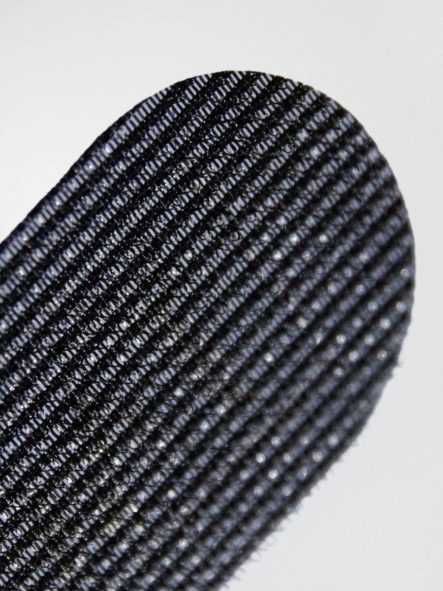 A close-up view of KOVI oval hair grippers showing the fine textured grip that prevents hair from slipping during extension installations. The durable, high-quality material makes it an essential tool for stylists working with wefts, tapes, and keratin bonds.